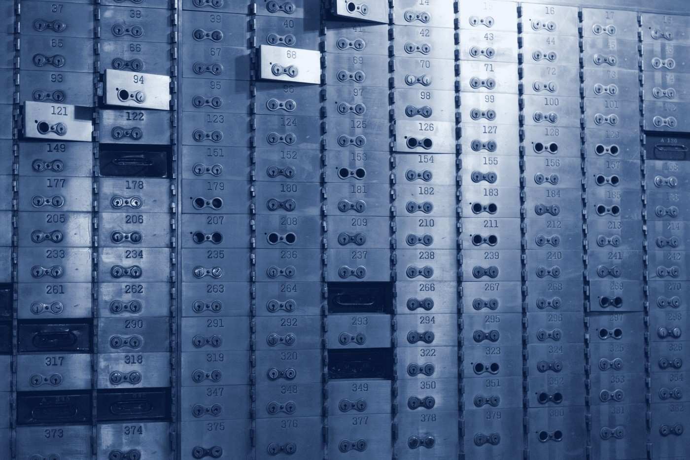 A wall of numbered metal safe-deposit boxes, each with two keyholes.