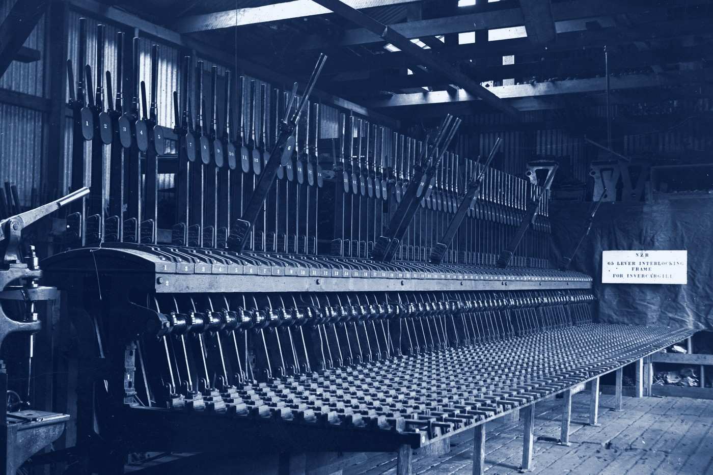 A long railway signal interlocking frame with a row of numbered levers in a workshop.