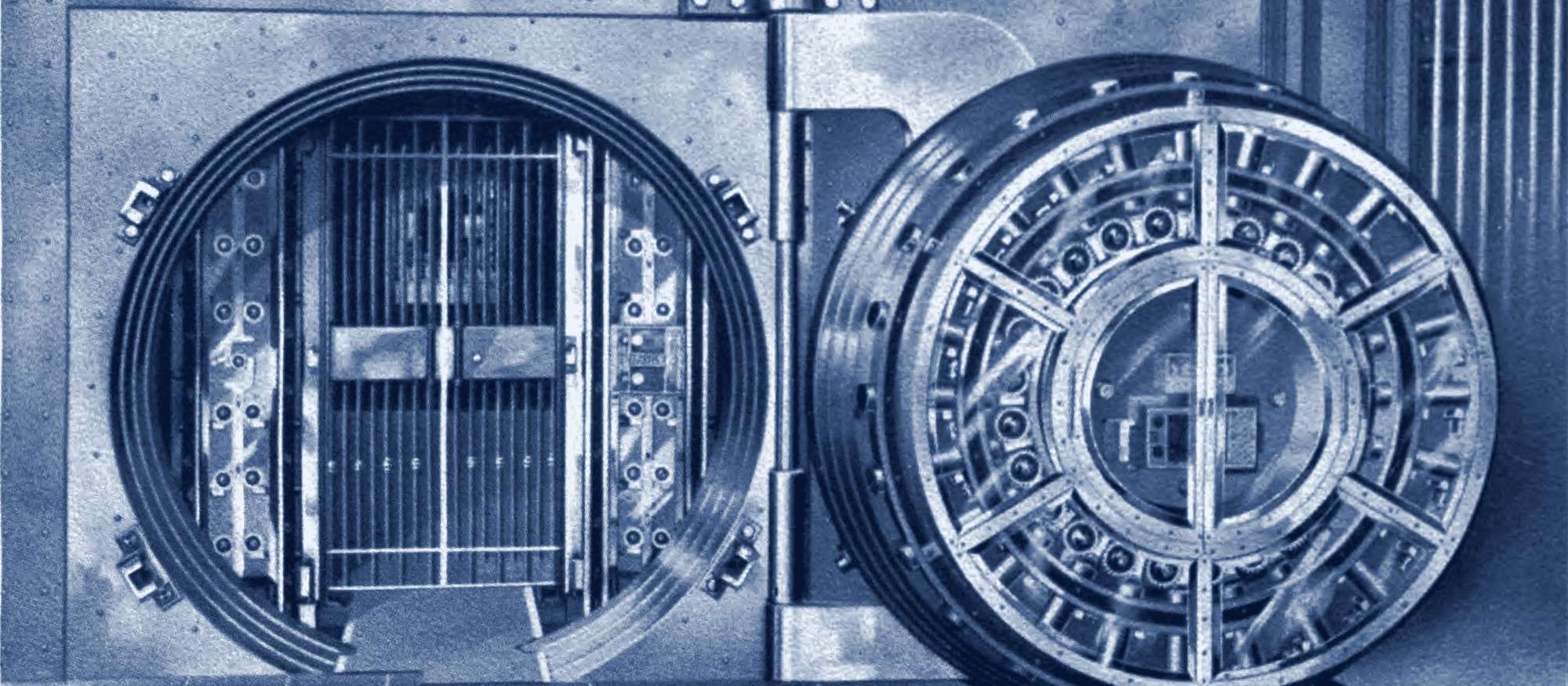 Round steel door of a bank safe-deposit vault standing open beside its barred inner gate.